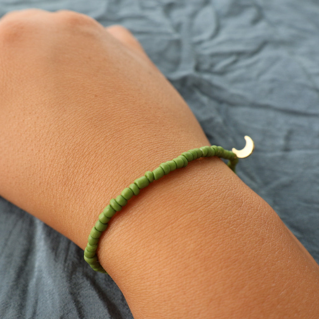 Handgjort grönt armband med guldfärgad berlock