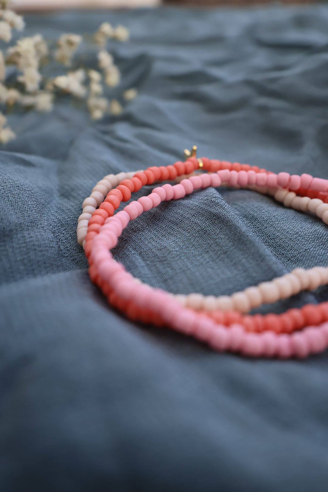 Handgjorda armband i vit, rosa och korall med guldfärgad berlock