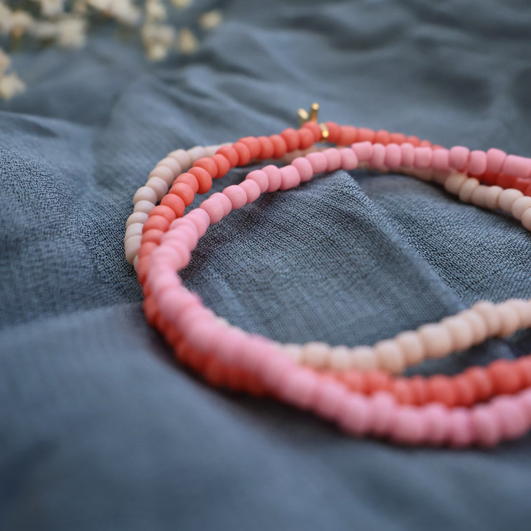 Handgjort rosa armband med små pärlor och guldfärgad berlock