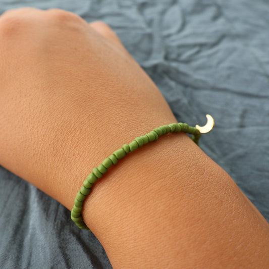 Handgjort grönt armband med guldfärgad berlock
