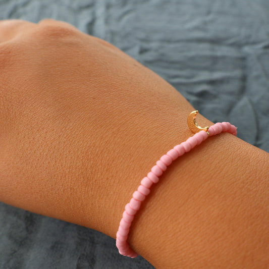 Handgjort rosa armband med små pärlor och guldfärgad berlock