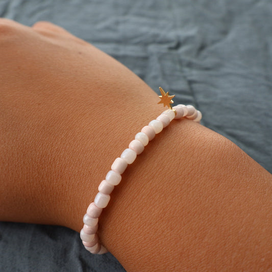 handgjort armband i beige med guldfärgad berlock